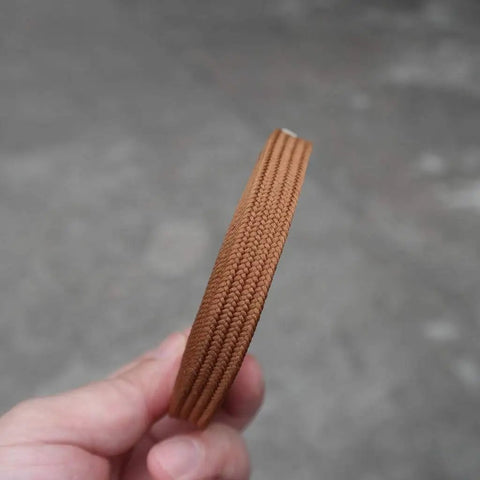 Close-up of Pro Grade Synthetic Silk Tsuka Ito Wrapping Cord 22.9ft in brown, held by a hand, showing texture and thickness.