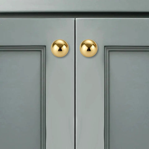 Two Pack One And A Quarter Inch Unlacquered Brass Cabinet Knobs Round Pulls shown on gray cabinet doors