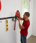 Man using FastTrack Garage Storage Rail System 7 Piece Hook Kit Heavy Duty Tool Organizer to hold a power tool on wall rail