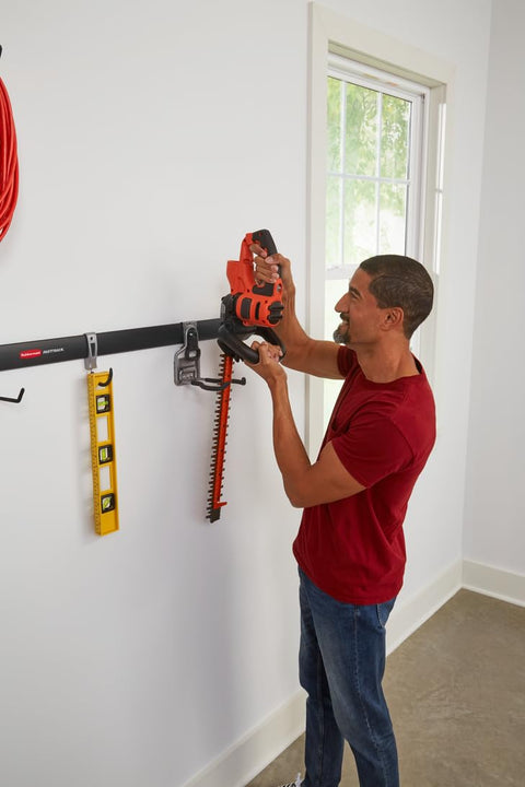 Man using FastTrack Garage Storage Rail System 7 Piece Hook Kit Heavy Duty Tool Organizer to hold a power tool on wall rail