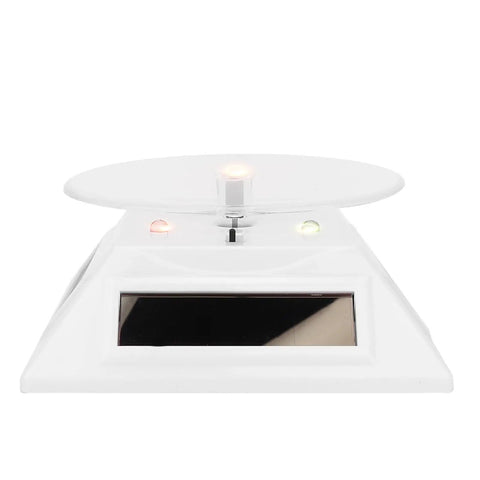 Xhtllo Electric Led Light Solar Powered Rotating Turntable Display Stand For Jewelry Phunique Watches Camera And Decorations front view with white base and acrylic top.