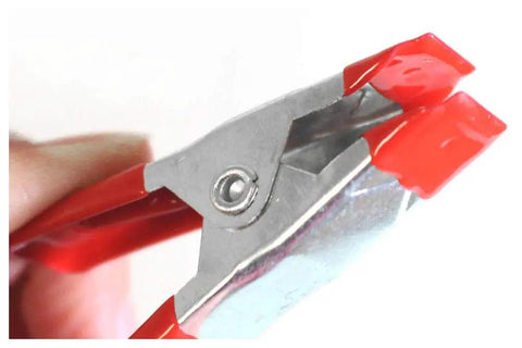 Close-up of 12 Pack 2 Inch Metal Spring Clamps With Built In Magnets For Magnetic Surfaces showing red grip and metal hinge