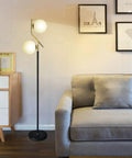 Two Milky White Glass Orbs Brass Finish Floor Lamp With Black Base, Modern Mid Century Style in a Living Room