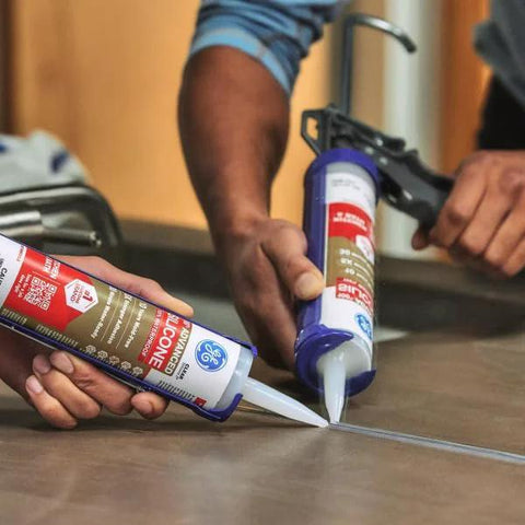 Two people applying Waterproof Kitchen And Bathroom Silicone Caulk White 10 Oz 1 Pack Strong Adhesion on a countertop.