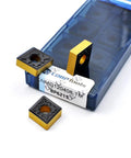 CNMG120408-TM carbide turning inserts in blue storage case; two yellow-coated inserts visible.