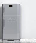Silver double-door refrigerator with a digital display on top, standing on a tiled floor in a minimalistic kitchen setting.