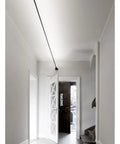 Effortlessly Sleek Modern Linear LED Wall Sconces With Remote Control For Cozy Bedroom And Living Room Vibes A Total Game Changer For Your Glow Up In Black Finish Dimmable Lighting illuminating a white hallway.