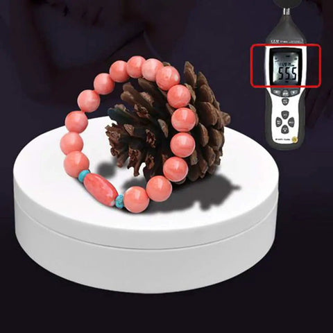 Luxury Electric Rotating Jewelry Display Stand With Mirrored Base, Smooth Spin Turntable For Rings, Necklaces & Watches on white box with coral bracelet.