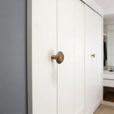 Retro Brass Cabinet Hardware Set with Greek Key Knobs on white closet door, showing hammered texture, zinc alloy drawer pulls