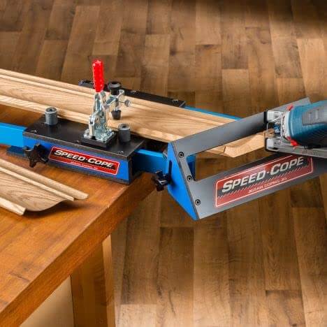 Speed Cope Crown Molding Jig With Adjustable Handle for DIY woodworking on a table, holding crown molding for cutting.