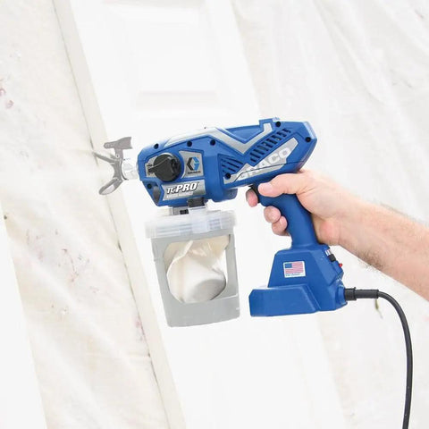 Professional Corded Airless Paint Sprayer With Triax Triple Piston Pump And Smart Control Dial held for easy use on a wall.