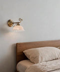 Ceramic Wall Sconce, 9 Inch Brass Vintage Light with floral shade illuminating a cozy bedroom beside the bed.