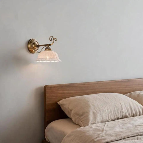 Ceramic Wall Sconce, 9 Inch Brass Vintage Light with floral shade illuminating a cozy bedroom beside the bed.