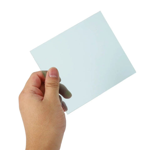 Hand holding a clear polycarbonate lens from the Premium Polycarbonate Welding Helmet Replacement Cover Lens Kit.
