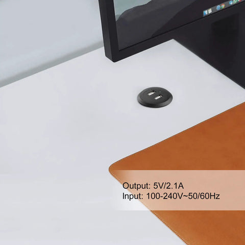 Recessed USB Power Grommet For Sleek Desk And Sofa Setup Featuring Built In Dual Fast Charging Ports With Totally Hidden Cord Routing For A Clean Game Vibe on a white desk next to a brown leather pad.