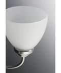 Close-up of etched glass shade on Five Light Etched Glass Farmhouse Chandelier In Brushed Nickel Finish With Scroll Arms.