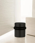 2 Pack Cylindrical Door Stops With Brass Construction And Oil Rubbed Bronze Finish floor mounted next to a door corner