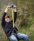 Man using 200 Ft Zip Line Kit With Adjustable Harness And Bungee Brake System for backyard fun, shown in action with blue trolley.