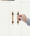 Hand holding Six Pack Solid Wood Cabinet Handles And Pulls 4.4 Inch Center To Center on white doors.