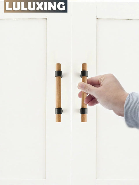 Hand holding Six Pack Solid Wood Cabinet Handles And Pulls 4.4 Inch Center To Center on white doors.