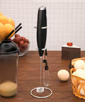 Automatic Milk Frother Wand for Lattes and Cappuccinos, Battery Operated Handheld Foam Maker on kitchen counter with fruits