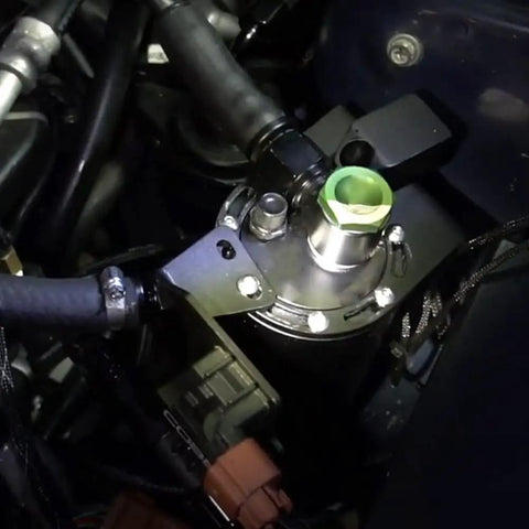 Yukofe Universal Air Oil Separator Catch Can installed in engine bay, black stainless steel construction preventing oil buildup.