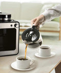Compact Drip Coffee Maker With Built In Grinder, Programmable Clock, Insulated Carafe, brewing coffee into two cups on table.