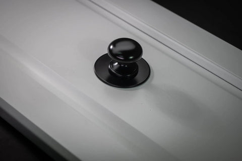 Matte Black Escutcheon Back Plates For Cabinet Knobs And Doors Four Pack Round Rosette Plate Two And One Third Inch Heavy Duty Die Cast Zinc Ideal For Bifold Closet Doors Door Pulls And Handles installed on a white cabinet door.