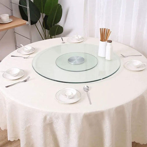 Slick Tempered Glass Lazy Susan Turntable For Kitchen Or Dining Table on a round white table with dishes and utensils.