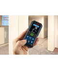 Person holding Blaze Green Beam Laser Measure Up To 165 Feet With Real Time Distance Reading, bright screen readout.