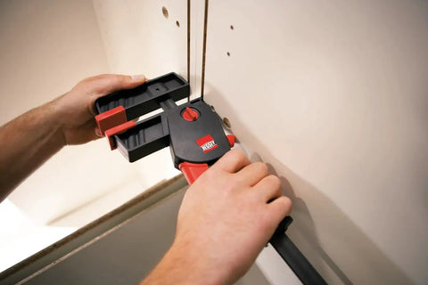 User demonstrating No Sweat One Hand Clamp And Spreader For Tough Woodworking 18 Inch Span securing wood pieces.