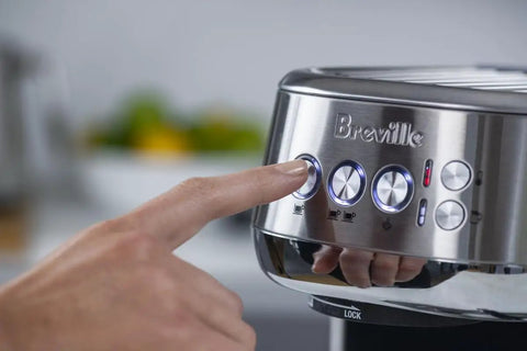 Close-up of a hand pressing buttons on the Damson Blue Kickass Espresso Coffee Maker Featuring Auto Milk Frother Quick Heat Technology.