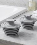 GLSTOY Silicone Bathtub Drain Plug 2 Pack Gray for 1.5 to 2 Inch Drains on marble countertop.