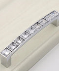 Close-up of Six Pack U Shape Crystal Glass Drawer Pull Knob with shiny silver handle and zinc alloy base on cabinet.