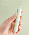 Close-up of a hand holding the 3 Pack 2 In 1 Needle Threader And Seam Ripper Set For Sewing Threading And Seam Removal Must Have Handy Tool.