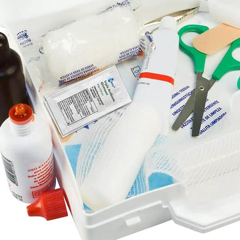 First aid kit contents with antibiotic ointment packets, small bottle, scissors, tape, and bandages
