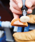Close-up of the 20 Piece Cleaning And Polishing Micro Kit for Rotary Tools restoring shine on a wooden object with a polishing wheel.