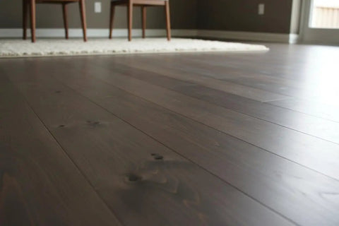 Pro Grade Reactive Water Based VOC Free Wood Stain For Pine on dark finished wood flooring in a modern interior setting.