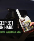 Top Shelf Diesel Fuel Additive And Daily Tune Up Formula Keeps Your Rig Running Slick Boosts Mileage And Sweeps Away Carbon Gunk For A Rock Solid Highway Cruise In A 16 Oz Bottle held near a vehicle fuel tank.