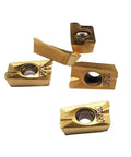 Five gold APMT1604 carbide turning inserts with central through-holes.