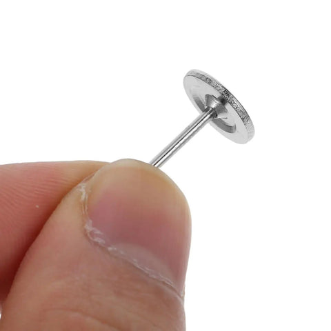 Closeup of sleek stainless steel upholstery tack held in finger for DIY projects. Kick Up Your DIY Game With Sleek Stainless Steel Upholstery Tacks Delivered Straight To Your Door With Top Shelf Decorative Furniture Nails Designed For Easy Sofa And Headboard Projects.
