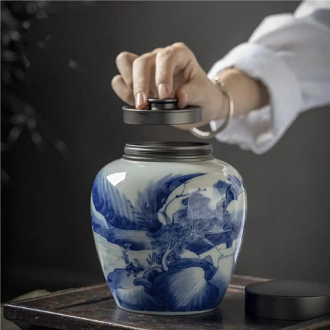 A hand removing the lid from a solid ceramic tea canister for loose leaf storage, retro minimalist design.