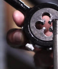 Close-up of 1-3/4-10 UNC Round Adjustable Die in use, threading metal rod, showcasing High Speed Steel HSS and bright finish.