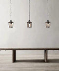 Three Dope Farmhouse Oak Wood Island Pendant Light With Bronze Finish hanging above wooden table in minimalistic room.