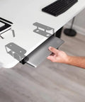 Hand installing the heavy duty under desk laptop holder and adjustable keyboard tray rack to toss desk clutter aside.