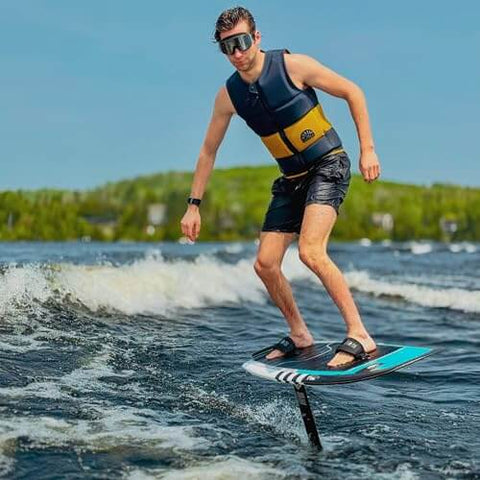 Man wearing Frameless Ultralight Black Mirror Swim Goggles With VisiClear Nanotech Anti Fog Lens And 100 Percent UV Protection surfing on water