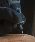 Dremel 729-01 carving/engraving micro kit close-up; engraving bit on wood with blue knob and gloved hand.
