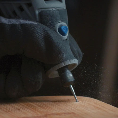 Dremel 729-01 carving/engraving micro kit close-up; engraving bit on wood with blue knob and gloved hand.
