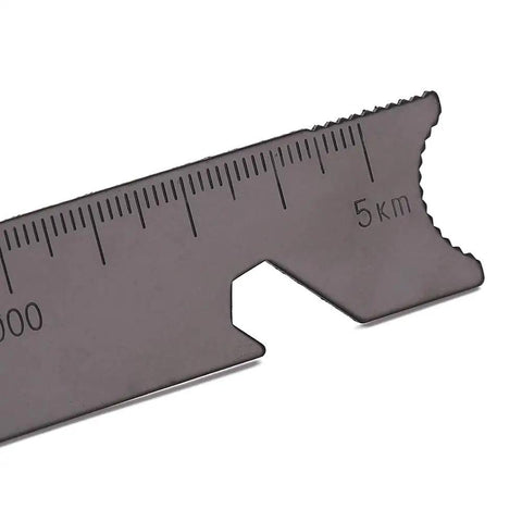 Close-up of multi function scraper from Grab And Go Emergency Fire Starter Kit with measurement markings, serrated edge visible.