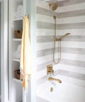 Modern bathroom with striped tile, champagne bronze fixtures, and Universal Showering Wall Elbow In Champagne Bronze With Lumicoat Finish For Hand Showers No Fuss Clean Modern Square Design Resists Mineral Buildup And Hard Water Stains Compatible With Most Hand Showers For New Construction Install.